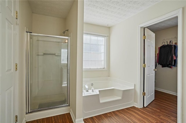 bathroom with a textured ceiling, shower with separate bathtub, and hardwood / wood-style floors