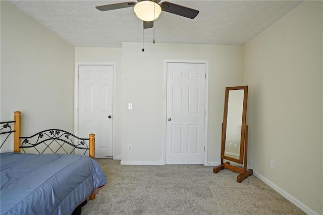 bedroom with ceiling fan, light carpet, and a textured ceiling