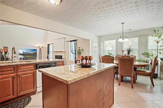 kitchen with dishwasher, a kitchen island, hanging light fixtures, light tile patterned floors, and a textured ceiling