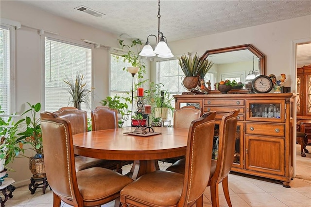 tiled dining space with a notable chandelier, a textured ceiling, and plenty of natural light