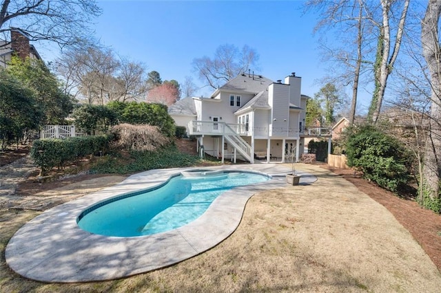 outdoor pool with a patio area, stairway, a wooden deck, and fence