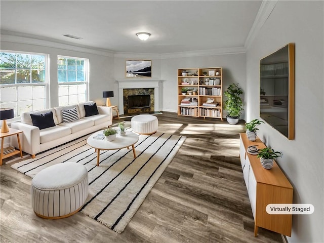 living room featuring a high end fireplace, visible vents, crown molding, and wood finished floors