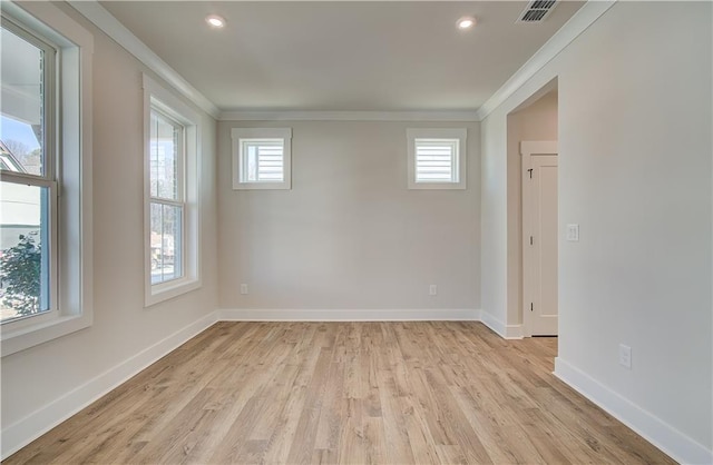 spare room with ornamental molding, visible vents, light wood-style flooring, and baseboards