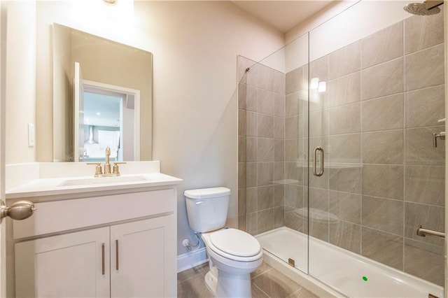 bathroom featuring toilet, a stall shower, baseboards, and vanity