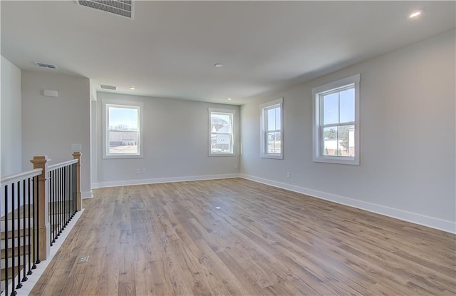 unfurnished room featuring visible vents, light wood-style flooring, and baseboards