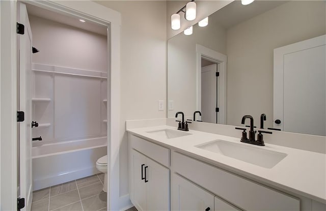 bathroom with double vanity, a sink, toilet, and tile patterned floors