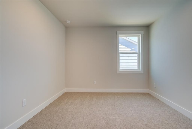 unfurnished room with baseboards and light colored carpet