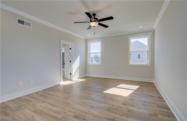 spare room with visible vents, ornamental molding, a ceiling fan, wood finished floors, and baseboards