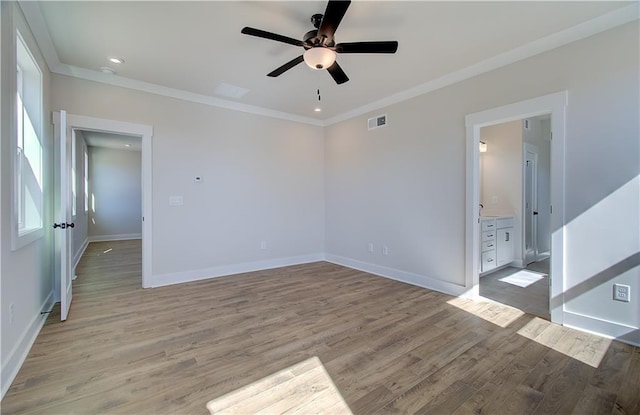 unfurnished room featuring ornamental molding, light wood-type flooring, visible vents, and baseboards