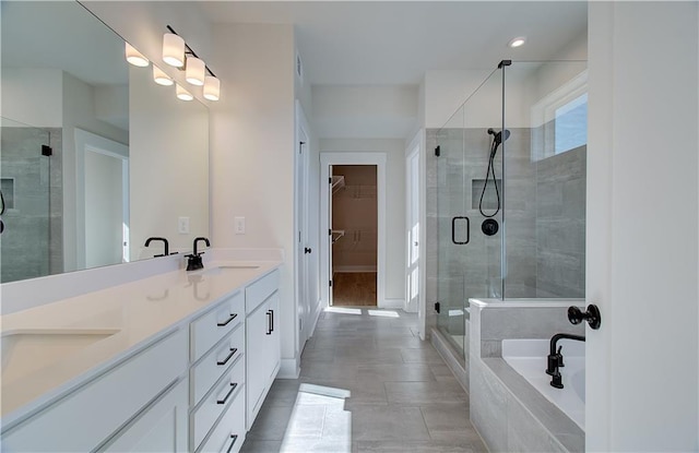 bathroom with a garden tub, a sink, double vanity, a stall shower, and a walk in closet