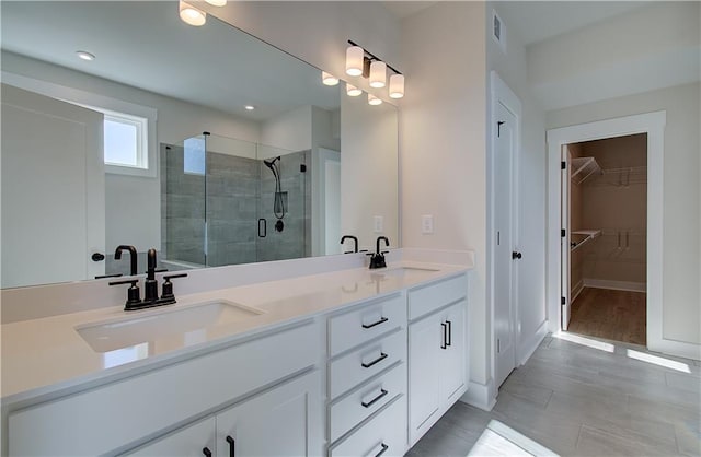 bathroom featuring visible vents, a sink, a shower stall, and double vanity