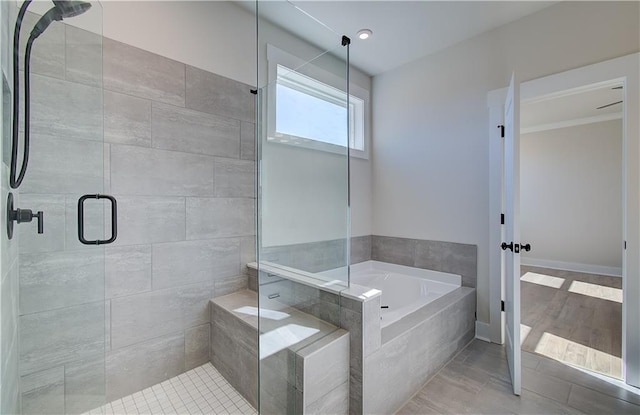 bathroom featuring a stall shower, baseboards, and a garden tub