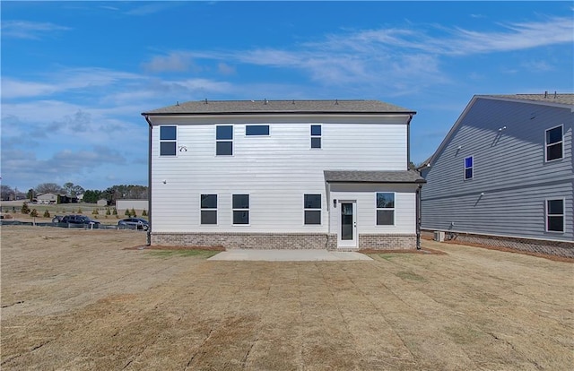 back of property with a yard, brick siding, and a patio