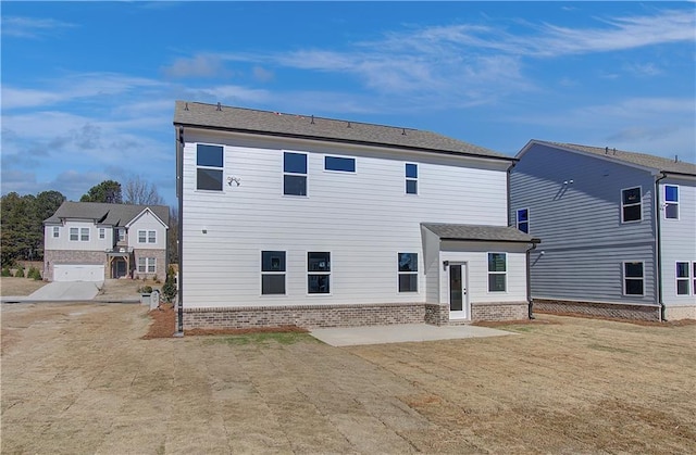 rear view of house featuring a yard, a patio area, and brick siding