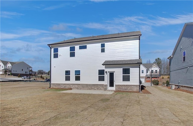 rear view of property featuring a lawn and brick siding