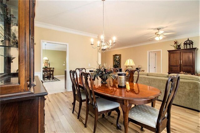 dining area featuring light wood-style flooring, crown molding, and ceiling fan with notable chandelier
