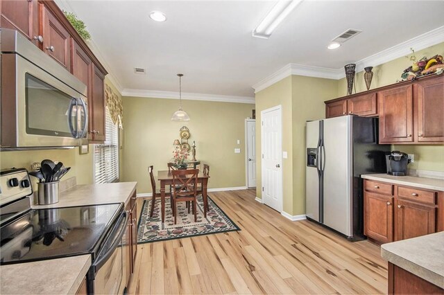 kitchen with crown molding, pendant lighting, appliances with stainless steel finishes, light wood-style flooring, and visible vents