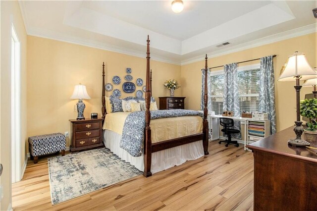 bedroom with visible vents, wood finished floors, ornamental molding, and a raised ceiling