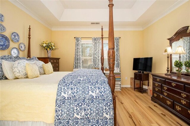 bedroom featuring baseboards, light wood finished floors, and a raised ceiling