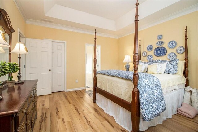 bedroom with baseboards, light wood-style flooring, crown molding, and a raised ceiling