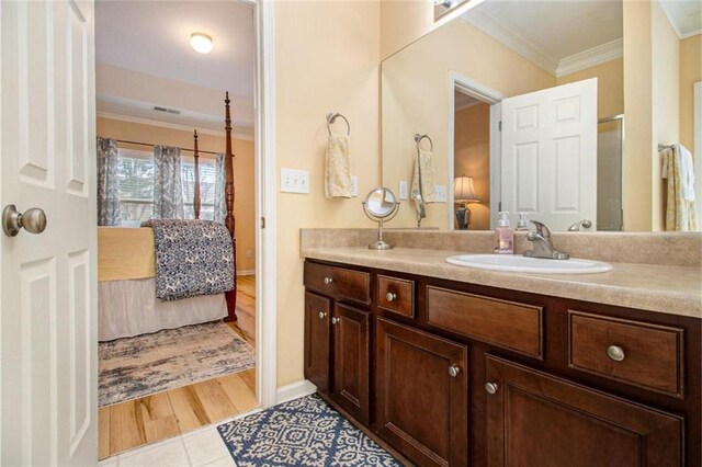 ensuite bathroom with connected bathroom, crown molding, vanity, tile patterned flooring, and baseboards