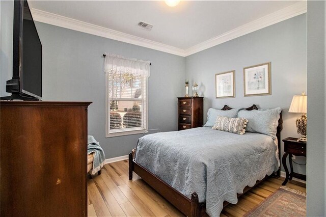 bedroom with baseboards, light wood-style flooring, visible vents, and crown molding