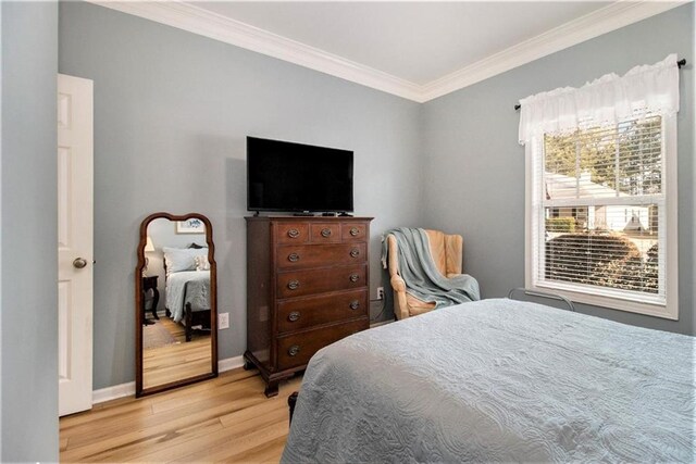bedroom featuring baseboards, crown molding, and light wood-type flooring