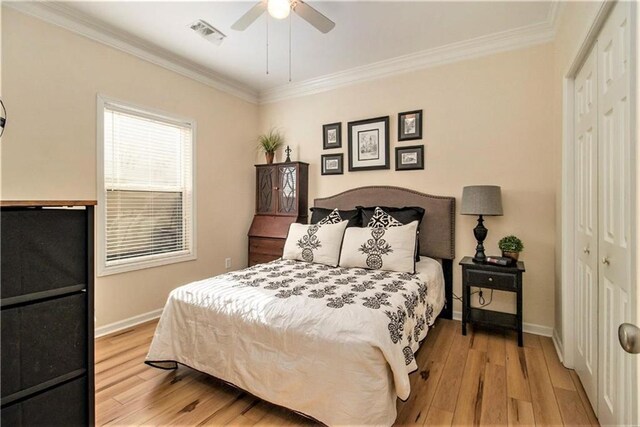 bedroom featuring wood finished floors, crown molding, and visible vents