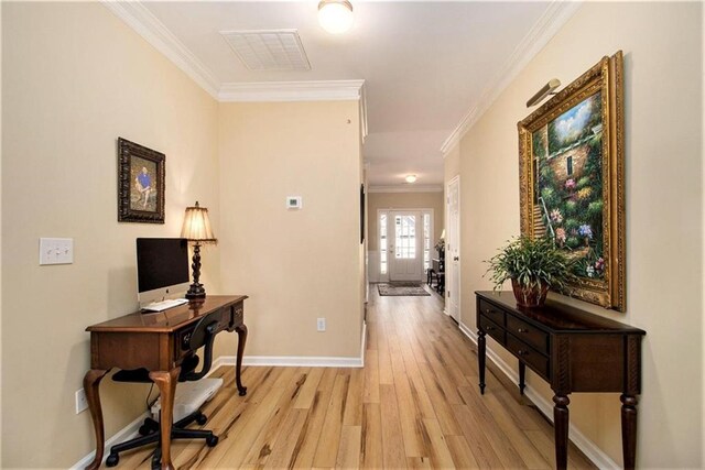 hallway with light wood-style flooring, ornamental molding, baseboards, and visible vents