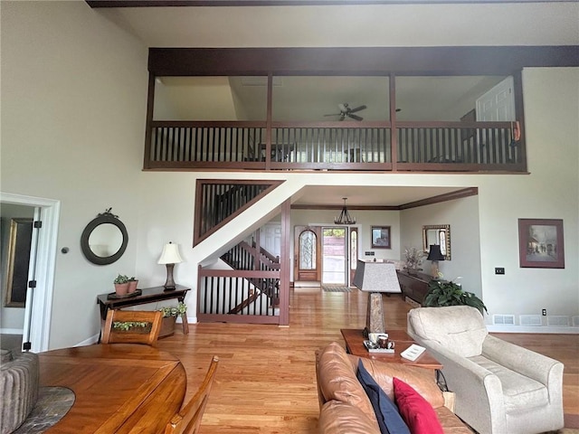 living room with stairway, wood finished floors, a towering ceiling, ceiling fan, and baseboards