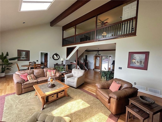 living room with wood finished floors, high vaulted ceiling, ceiling fan, beamed ceiling, and stairway