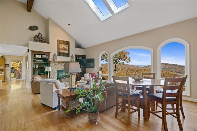 72 Wild Cherry Ln, Big Canoe, GA 30143 - living room featuring high vaulted ceiling, light wood finished floors, a stone fireplace, a skylight, and beamed ceiling