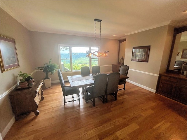dining room featuring crown molding, a chandelier, light wood-type flooring, and baseboards