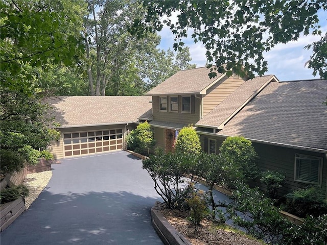 view of front of property with asphalt driveway, a garage, and roof with shingles