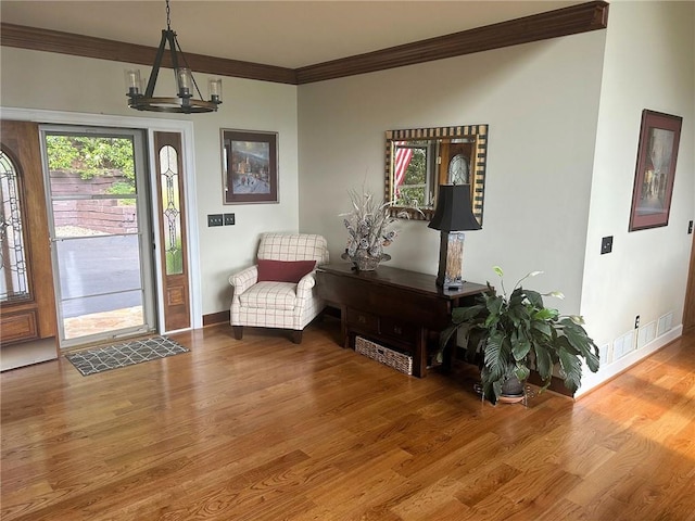 foyer entrance featuring crown molding, wood finished floors, a chandelier, and baseboards