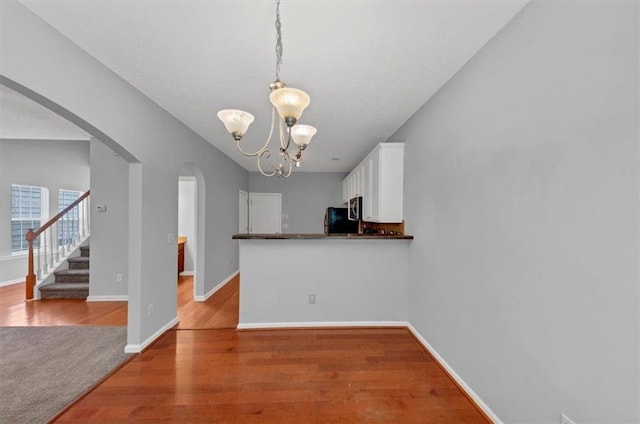 2165 Capella Cir S, Fulton, GA 30331 - kitchen featuring arched walkways, white cabinetry, a chandelier, freestanding refrigerator, and wood finished floors