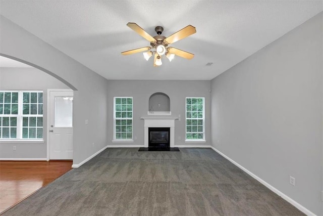 2165 Capella Cir S, Fulton, GA 30331 - unfurnished living room featuring ceiling fan, a glass covered fireplace, plenty of natural light, carpet flooring, and a textured ceiling