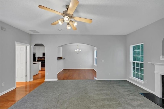 2165 Capella Cir S, Fulton, GA 30331 - unfurnished living room featuring arched walkways, carpet floors, a chandelier, a fireplace, and a ceiling fan