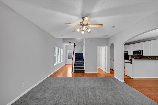 2165 Capella Cir S, Fulton, GA 30331 - unfurnished living room featuring light carpet, ceiling fan, arched walkways, stairway, and light wood finished floors