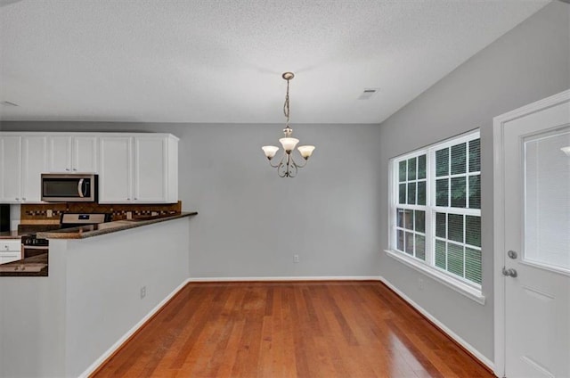 2165 Capella Cir S, Fulton, GA 30331 - kitchen featuring stainless steel microwave, white range with electric cooktop, a chandelier, dark countertops, and decorative backsplash