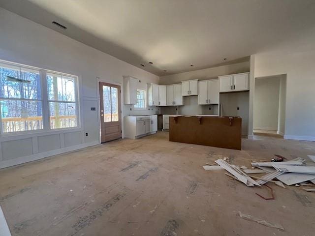 kitchen featuring baseboards, open floor plan, white cabinets, and a center island