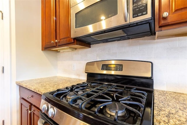 interior details featuring tasteful backsplash, light stone countertops, and appliances with stainless steel finishes