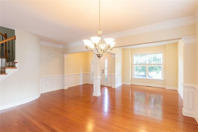 spare room featuring ornate columns, wood-type flooring, and crown molding