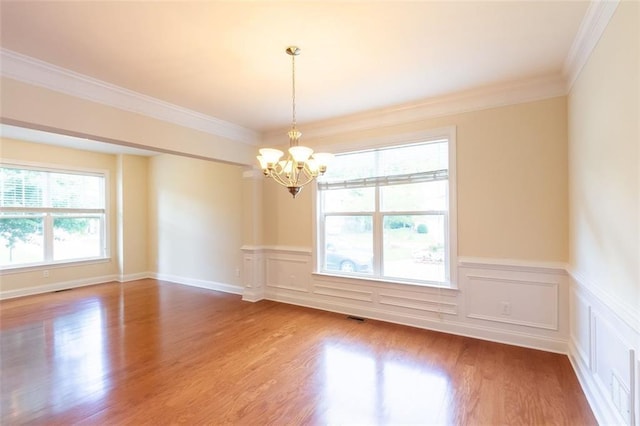 unfurnished room with wood-type flooring, a notable chandelier, and crown molding