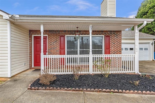 entrance to property featuring a porch, brick siding, a chimney, and a garage