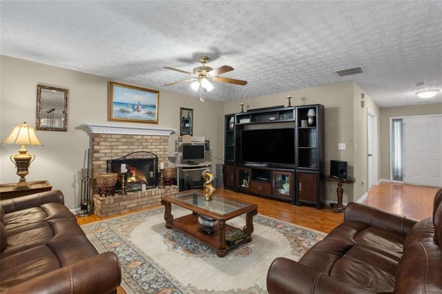 living room featuring visible vents, a fireplace, a textured ceiling, and wood finished floors