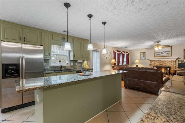 kitchen featuring a fireplace, light tile patterned flooring, green cabinets, and stainless steel fridge with ice dispenser