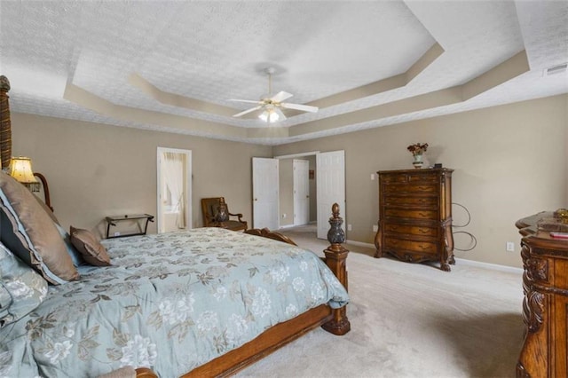 bedroom with baseboards, ceiling fan, a tray ceiling, a textured ceiling, and carpet flooring