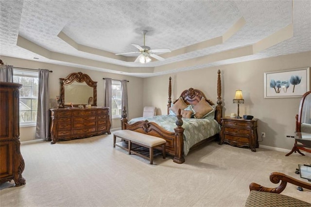 carpeted bedroom featuring baseboards, a tray ceiling, and a textured ceiling