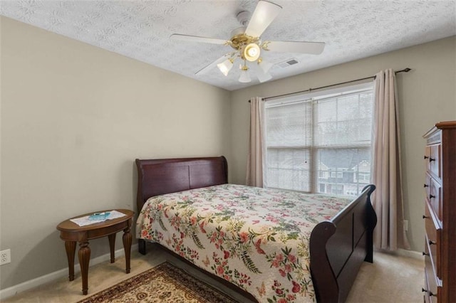 bedroom with a textured ceiling, ceiling fan, light colored carpet, visible vents, and baseboards